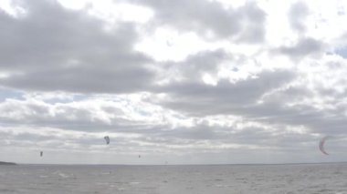 Atletler uçurtma sörfüne biner. Kiev Denizi. Yaz. Rüzgarlı bir hava. Rekabet. Renkli yelkenler. Havadan. Ukrayna. Kyiv.