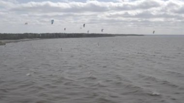 Atletler uçurtma sörfüne biner. Kiev Denizi. Yaz. Rüzgarlı bir hava. Rekabet. Renkli yelkenler. Havadan. Ukrayna. Kyiv.