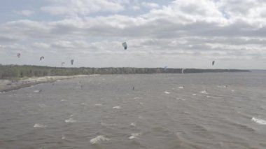 Atletler uçurtma sörfüne biner. Kiev Denizi. Yaz. Rüzgarlı bir hava. Rekabet. Renkli yelkenler. Havadan. Ukrayna. Kyiv.