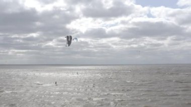 Atletler uçurtma sörfüne biner. Kiev Denizi. Yaz. Rüzgarlı bir hava. Rekabet. Renkli yelkenler. Havadan. Ukrayna. Kyiv.