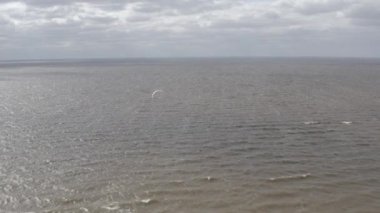 Atletler uçurtma sörfüne biner. Kiev Denizi. Yaz. Rüzgarlı bir hava. Rekabet. Renkli yelkenler. Havadan. Ukrayna. Kyiv.