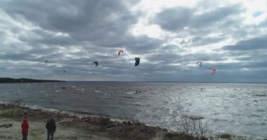 Atletler uçurtma sörfüne biner. Kiev Denizi. Yaz. Rüzgarlı bir hava. Rekabet. Renkli yelkenler. Havadan. Ukrayna. Kyiv.