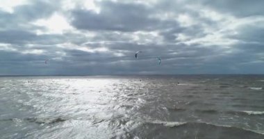 Atletler uçurtma sörfüne biner. Kiev Denizi. Yaz. Rüzgarlı bir hava. Rekabet. Renkli yelkenler. Havadan. Ukrayna. Kyiv.