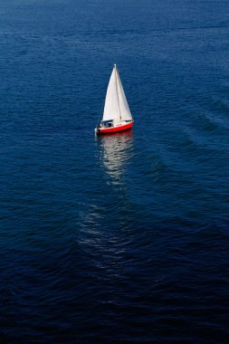 Sakin mavi bir denizde yalnız beyaz bir yelken
