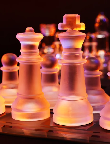 Glas chess på ett schackbräde upplyst av ett blått och orange ljus — Stockfoto