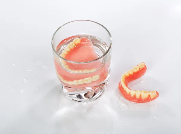 Un ensemble de prothèses dentaires dans un verre d'eau — Photo