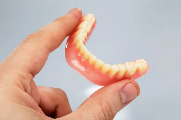 Mão segurando um conjunto de dentaduras — Fotografia de Stock