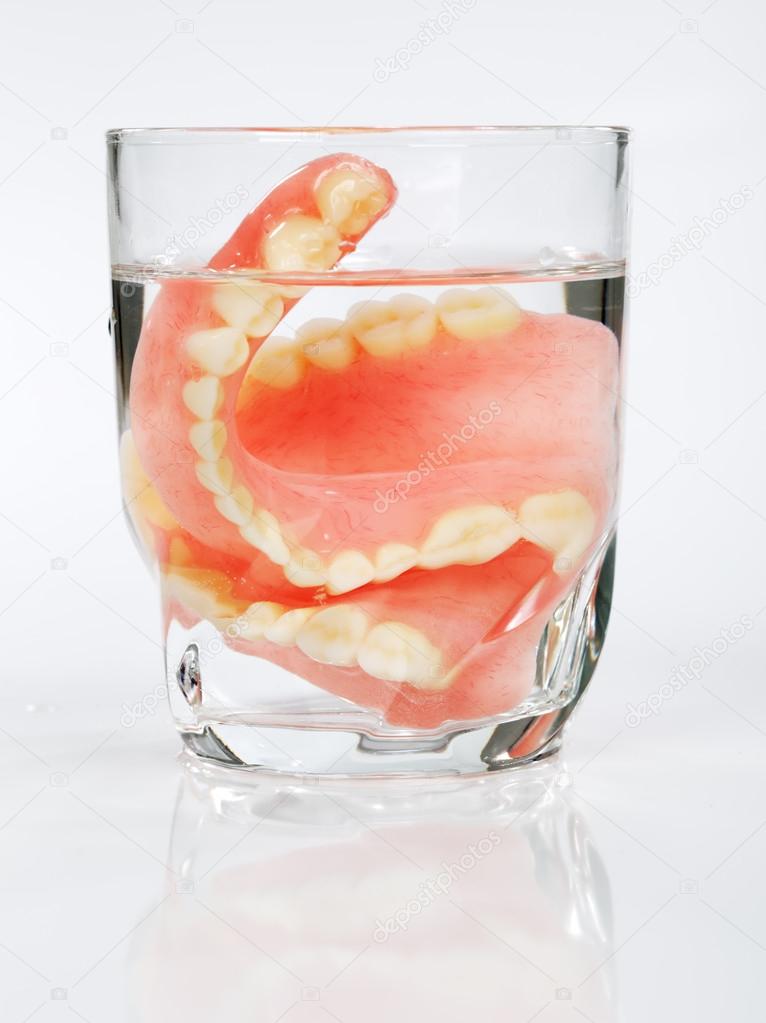 A set of dentures in a glass of water