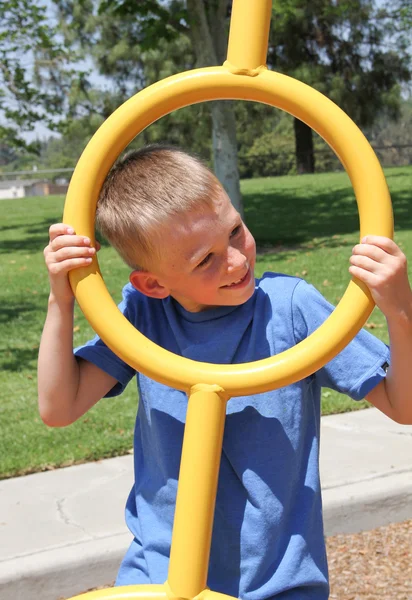 Boy climbing on monkey bars in park — Stock Photo, Image