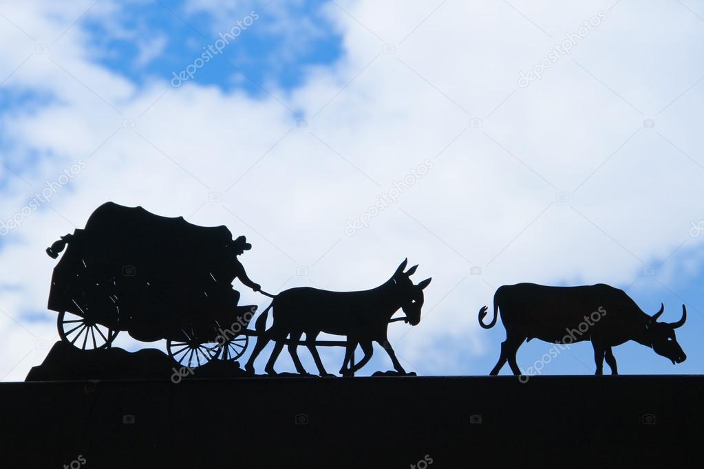Covered wagon silhouetted with blue sky