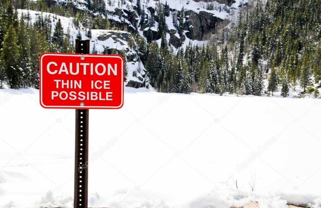 Danger thin ice sign with snowy lake