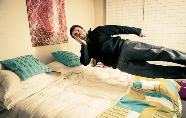 Man thinking while levitating over bed