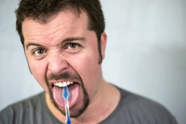 Angry man brushing his tongue — Stock Photo, Image