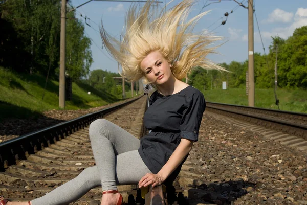 Девушка-блондинка сидит на рельсах — стоковое фото