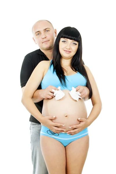 Pregnant girl with her husband and baby shoes — Stock Photo, Image