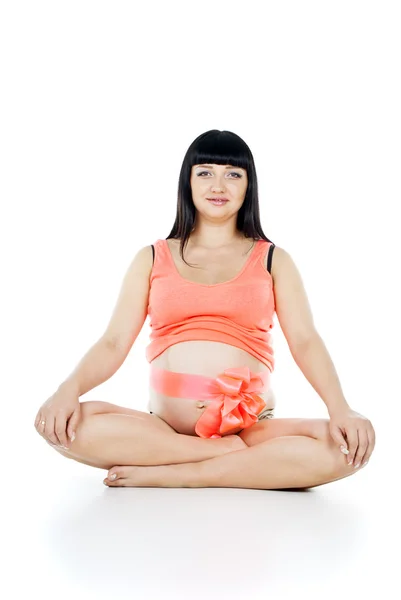 Беременная девушка с лентой на животе сидит — стоковое фото