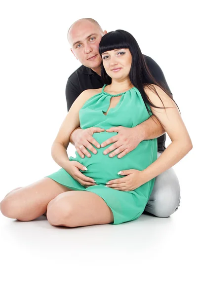 Happy pregnant couple hugging sitting on the floor Stock Picture