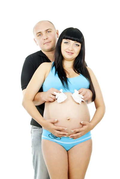 Pregnant girl with her husband and baby shoes Royalty Free Stock Images