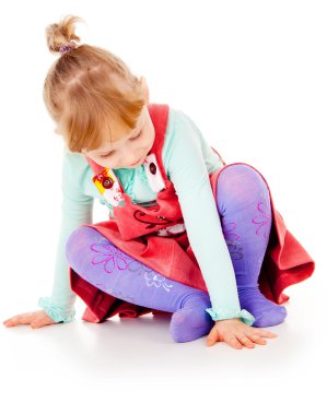 Kırmızı elbiseli, oturan küçük bir kız poz veriyor