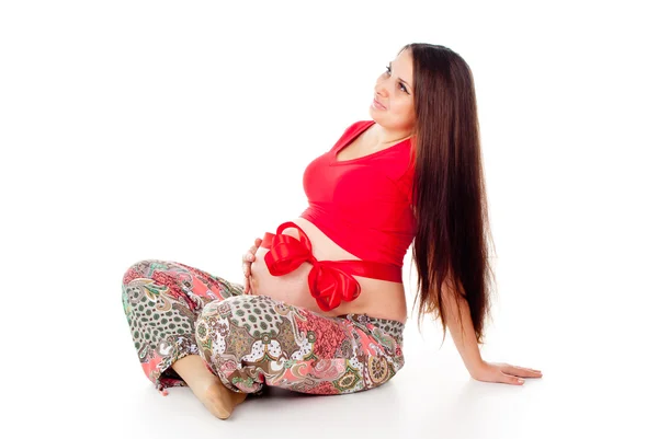 Pregnant girl with a red bow on her stomach — Stock Photo, Image