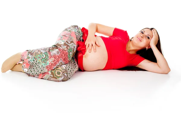 Pregnant girl, lies with a red ribbon on his stomach — Stock Photo, Image