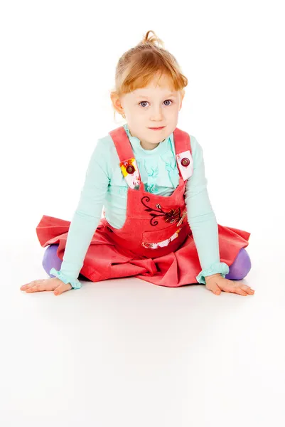 Uma menina em um vestido vermelho, sentado poses — Fotografia de Stock