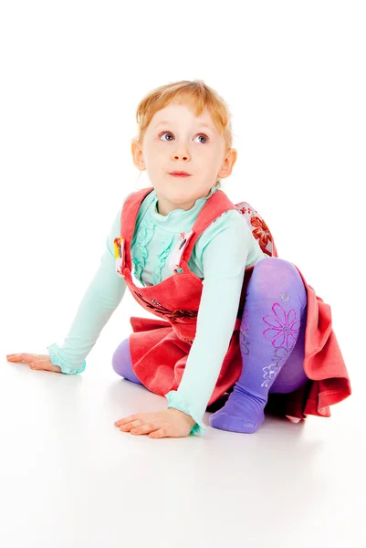 A little girl in a red dress, sitting poses — Stock Photo, Image