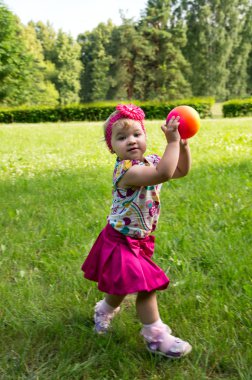 Küçük kız topla oynuyor.