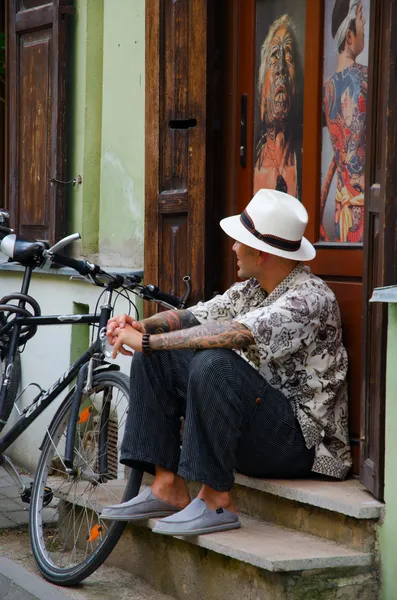 Young man with tattoos sitting near the door of tattoo studio