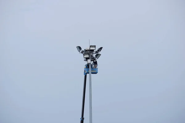 Workers equipped with helmets and safety equipment installed new diode lights. Workers in light poles repair lifting buckets