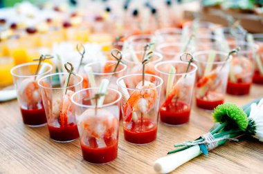 Beautiful row line of different alcohol and non-alcohol cocktails. Snack cocktails with tomato juice and shrimps. Catering table for party.