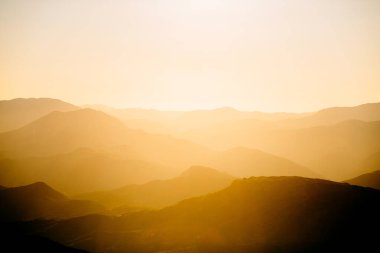 Beautiful orange sunset in mountains. Travel background. silhouettes of the mountings on sunrise. Nemrut Dag, Turkey