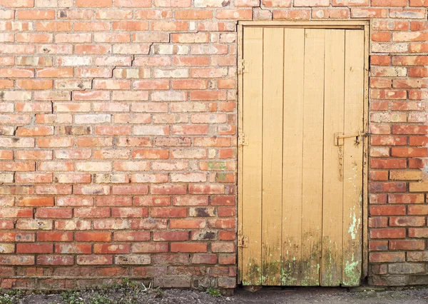 Puerta de madera del tablón, pared de ladrillo — Foto de Stock