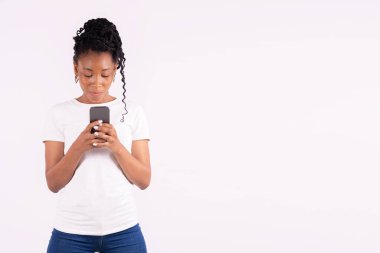 Sakin Afro-Amerikan kadın iki eliyle telefonunu kullanıyor ve tutuyor.