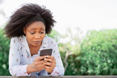  Cep telefonu ekranına şok olmuş bir ifadeyle bakan kadın.