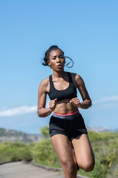 Mujer afroamericana corriendo rápido por una pasarela de madera: concepto de ejercicio. Imagen de stock