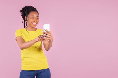 Güzel bir kadın telefonuna dokunurken gülüyor.