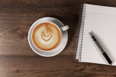 Not defteri ve dolma kalemle kahve fincanı.