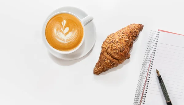 Croissant mit Kaffeetasse und Notizbuch — Stockfoto