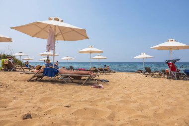 Güneşli yaz gününde kumsaldaki turistlerin güzel manzarası. Yunanistan. Nea Potidaea. 09.03.2021.