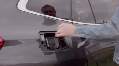 Elektrikli araba şarj istasyonuna kablo bağlayan adamın yakın görüntüsü. İsveç. 