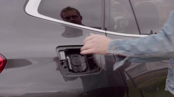 充電ケーブルを電気自動車の充電ステーションに接続する男のビューを閉じます スウェーデン — ストック動画