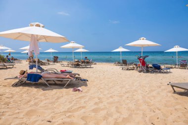 Güneşli yaz gününde kumsaldaki turistlerin güzel manzarası. Yunanistan. Nea Potidaea. 03.09.2021.