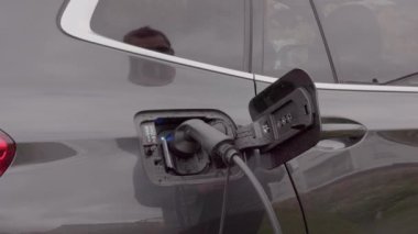 Elektrikli araba şarj istasyonuna kablo bağlayan adamı kapatın. İsveç. 
