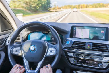 Elektrikli araba BMW iX3 'ün direksiyonundaki kadın ellerinin yakın görüntüsü. İsveç. Uppsala. 10.28.2021.