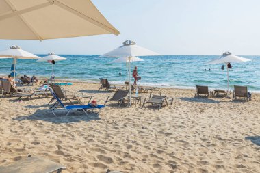 Güneşli yaz gününde kumsaldaki turistlerin güzel manzarası. Yunanistan. Nea Potidaea. 09.15.2021.