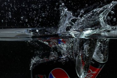 Coca Cola kutusunun yakın görüntüsü, pepsi kolanın siyah arkaplanda su izolasyonuna düşüşü. İsveç. Uppsala. 11.06.2021.