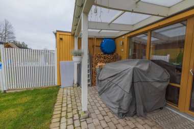 Sonbahar günü özel evin arka bahçesinin güzel manzarası. Yazlık mobilyalar örtülü, ahşap ahşap duvarlar arka planda. İsveç.