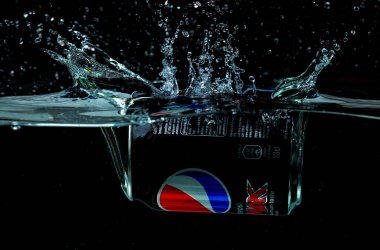 Pepsi Cola 'nın siyah arka planda su izolasyonuna düşüşünün güzel manzarası. İsveç. Uppsala. 11.14.2021.