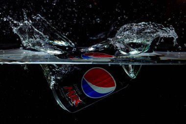 Pepsi Kola 'nın siyah arkaplanda su izolasyonuna düşüşünün yakın görüntüsü. İsveç. Uppsala. 11.24.2021.
